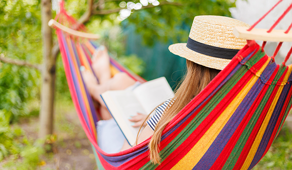 Woman in a colorful hammock relaxing and reading a book