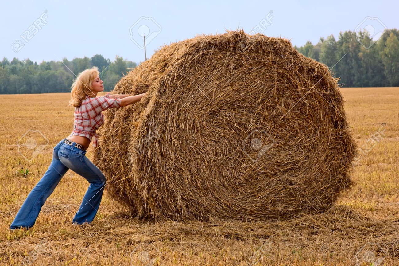 5528152-Young-woman-is-pushing-bale-of-straw-Stock-Photo-cowgirl-hay-straw.jpg